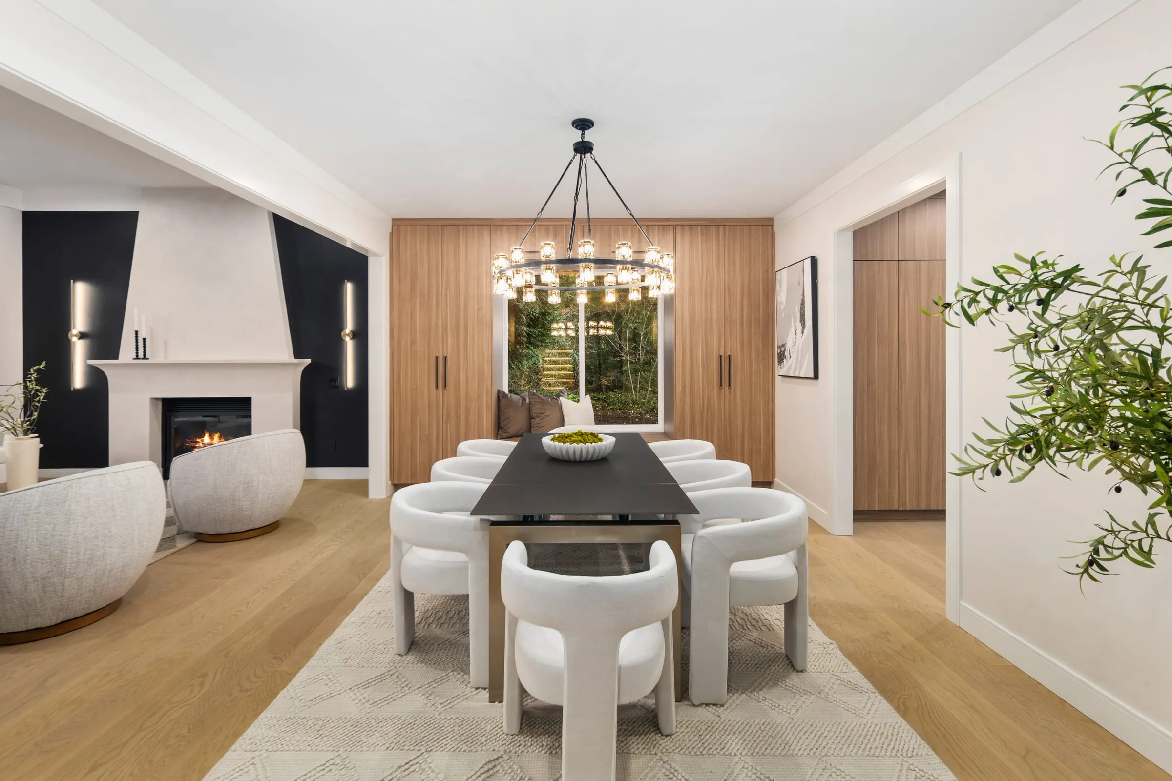 Dining room with a black table, sculptural chairs and a black iron ring chandelier