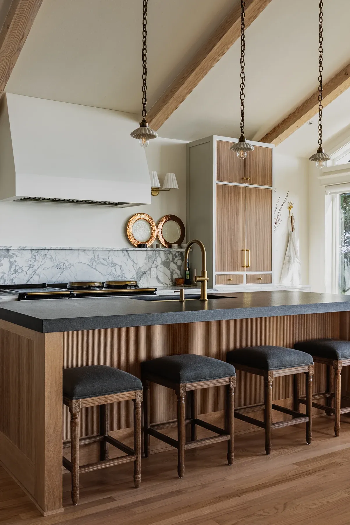 Kitchen with a wood island, bar stools and exposed ceiling beams, photographed by RE-MEDIA