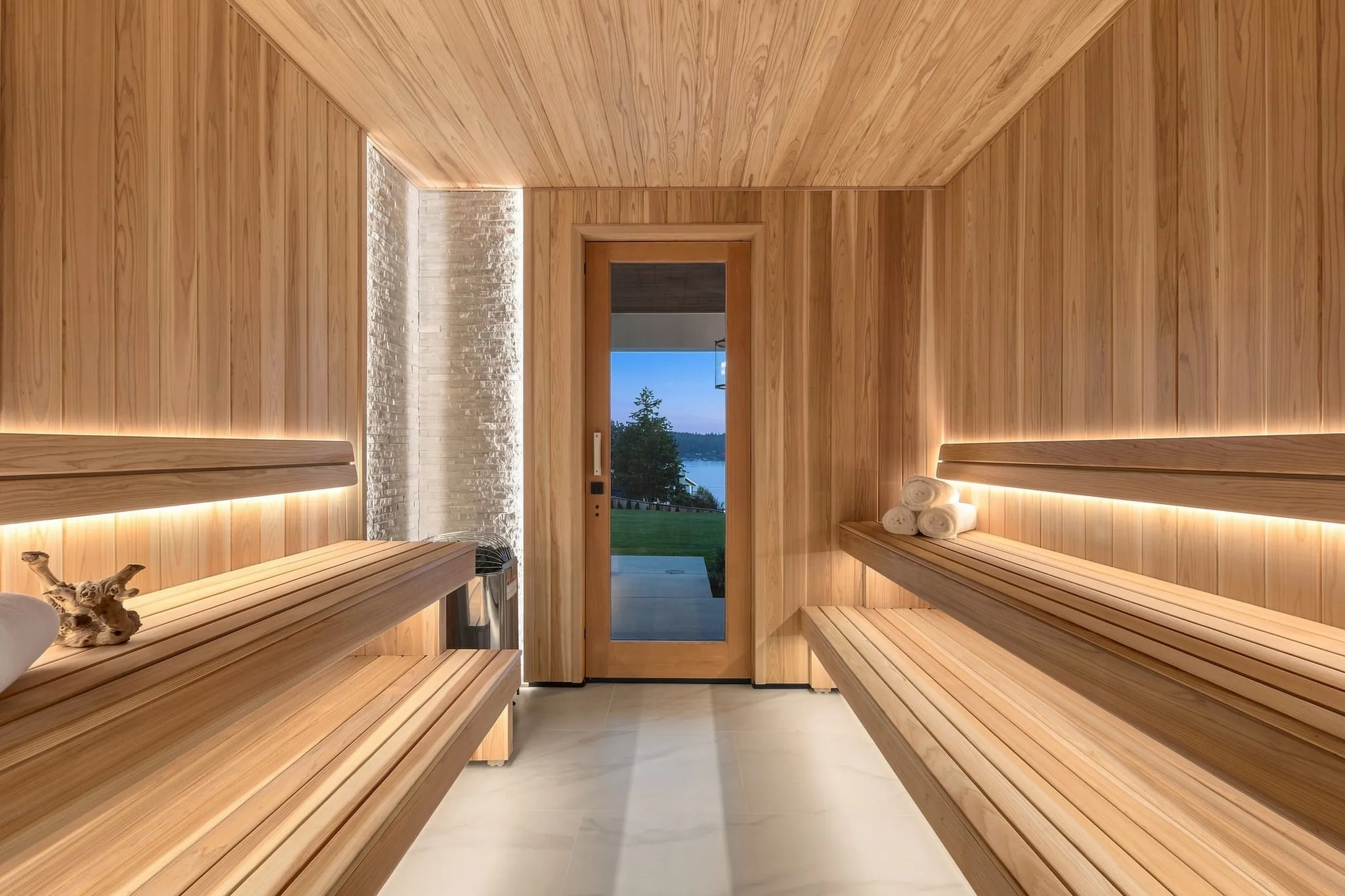 Cedar sauna with tiered benches and a glass door onto the lake