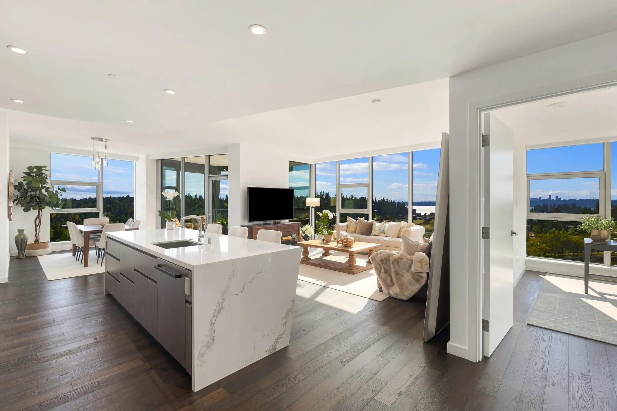 High-rise condo kitchen with a waterfall island and forest views