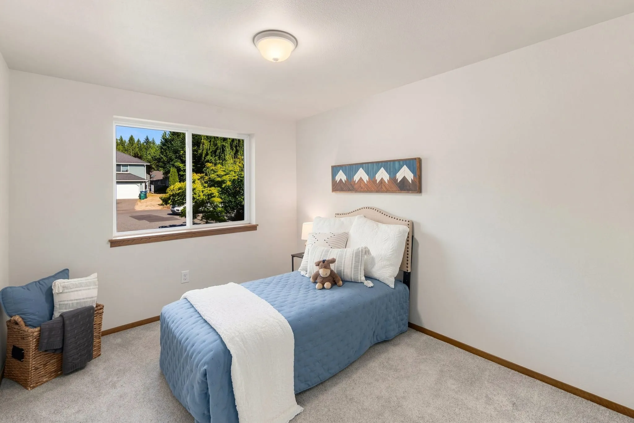 Staged kids bedroom with a blue quilt and mountain wall art
