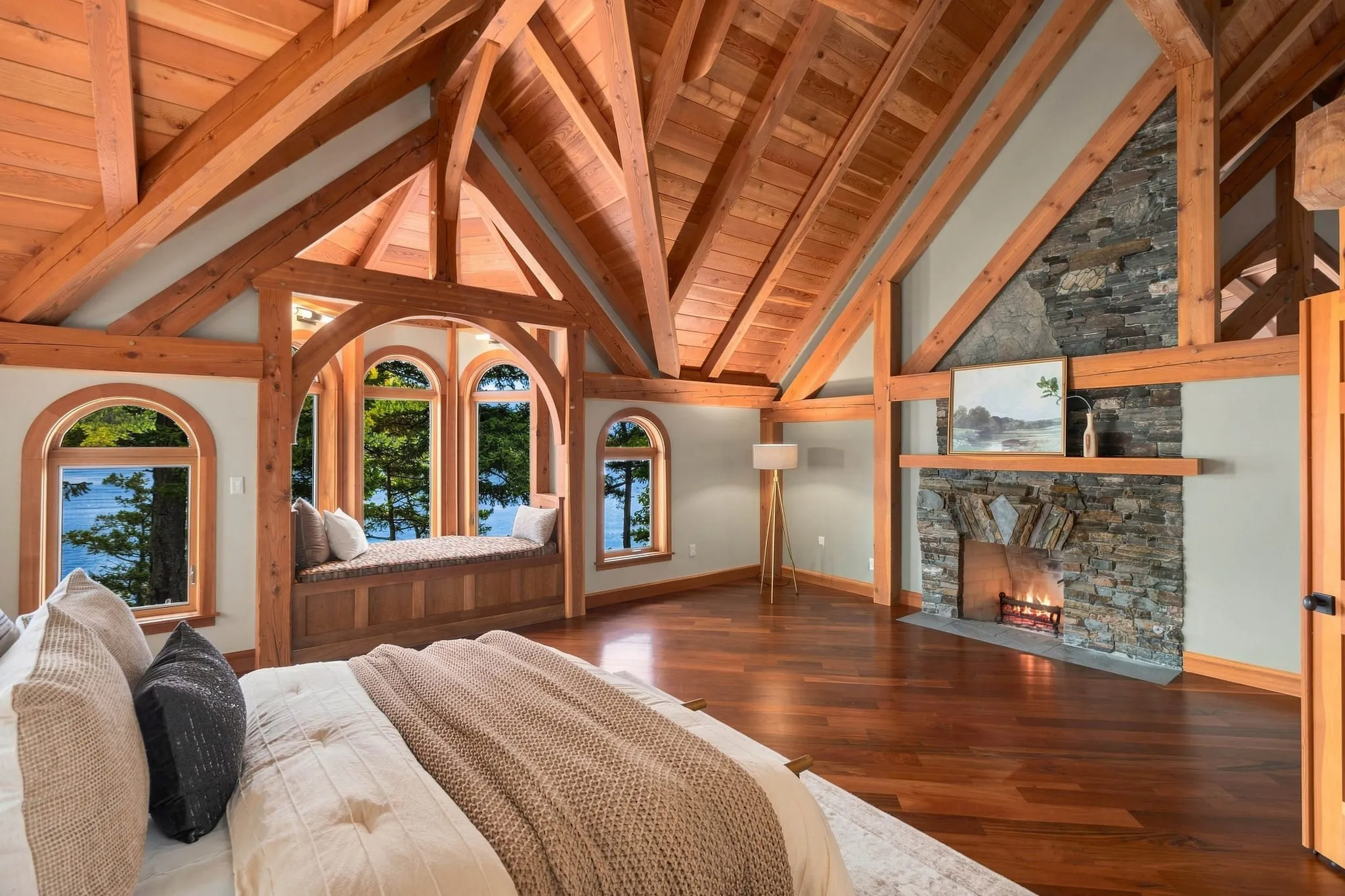 Timber-frame primary bedroom with a stone fireplace