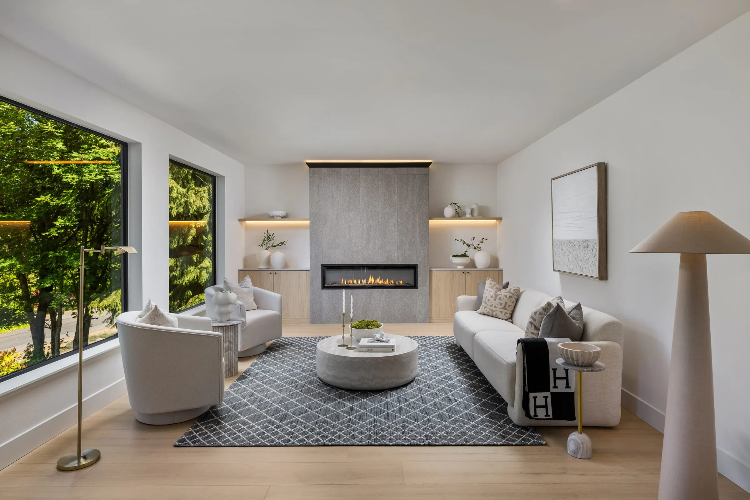 Living room with a linear gas fireplace, backlit niches and floor-to-ceiling windows