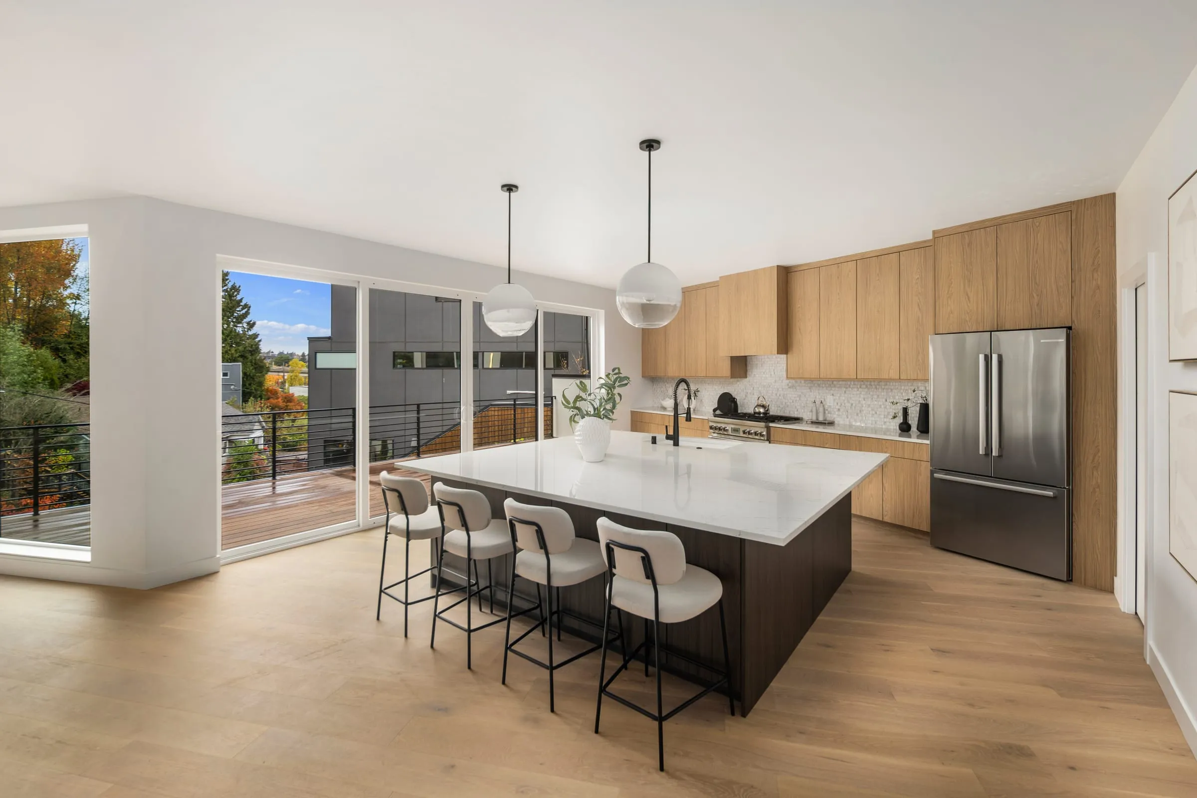 Contemporary kitchen with a waterfall island, globe pendants and sliding doors to a deck