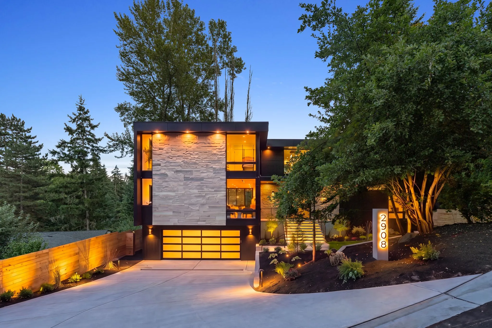 Twilight exterior of a modern cedar and black home, lit from within, shot by ACRE Seattle