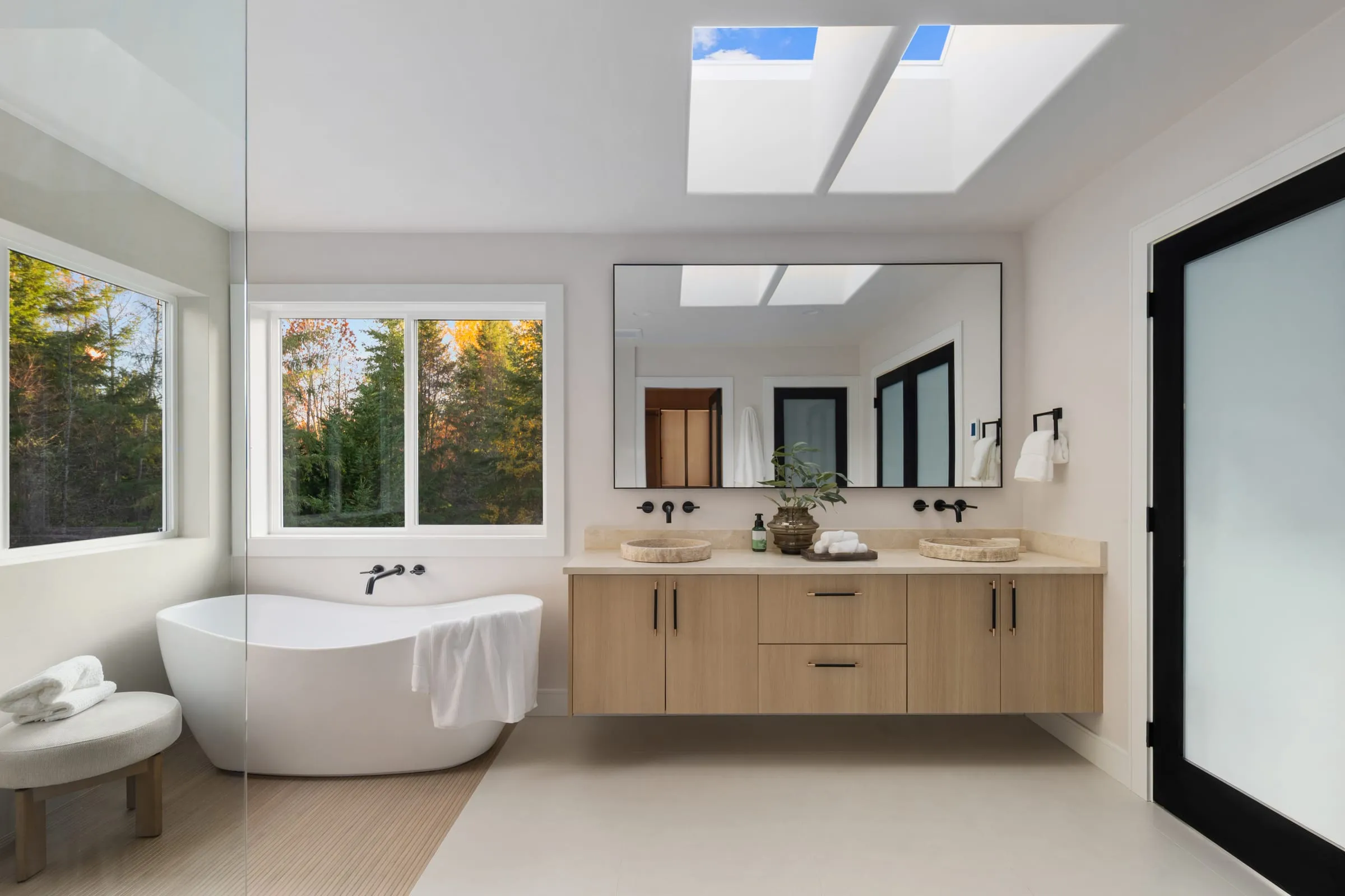 Primary bathroom with a freestanding tub under a window and a double oak vanity
