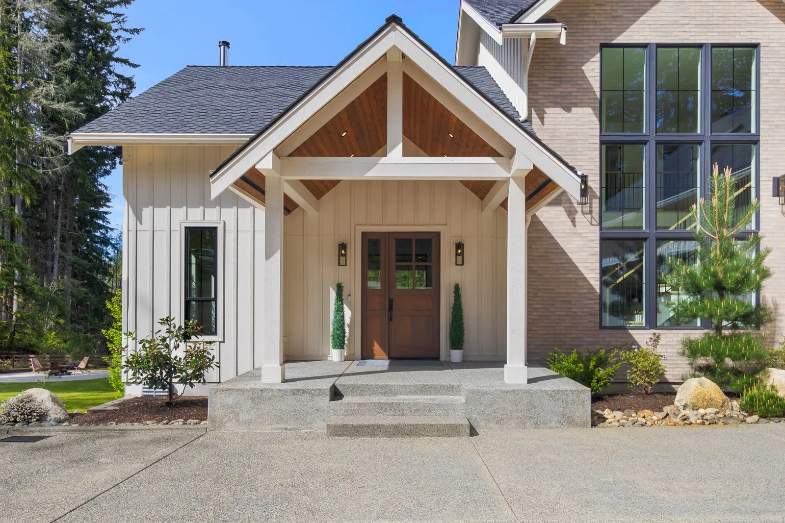 Craftsman entry porch with a timber gable, stone columns and a lit front door