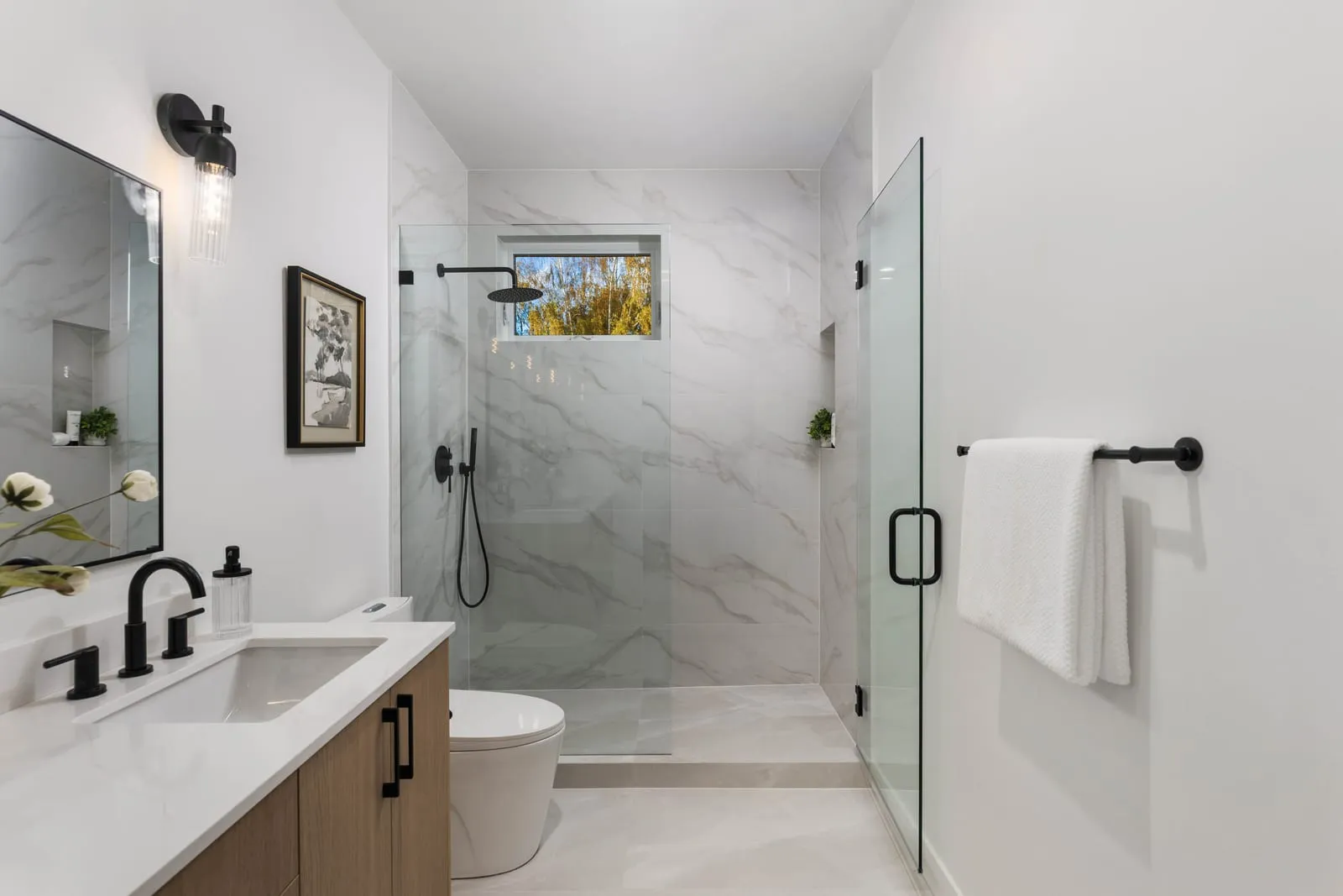 Bathroom with a marble-look walk-in shower, black fixtures and a window above