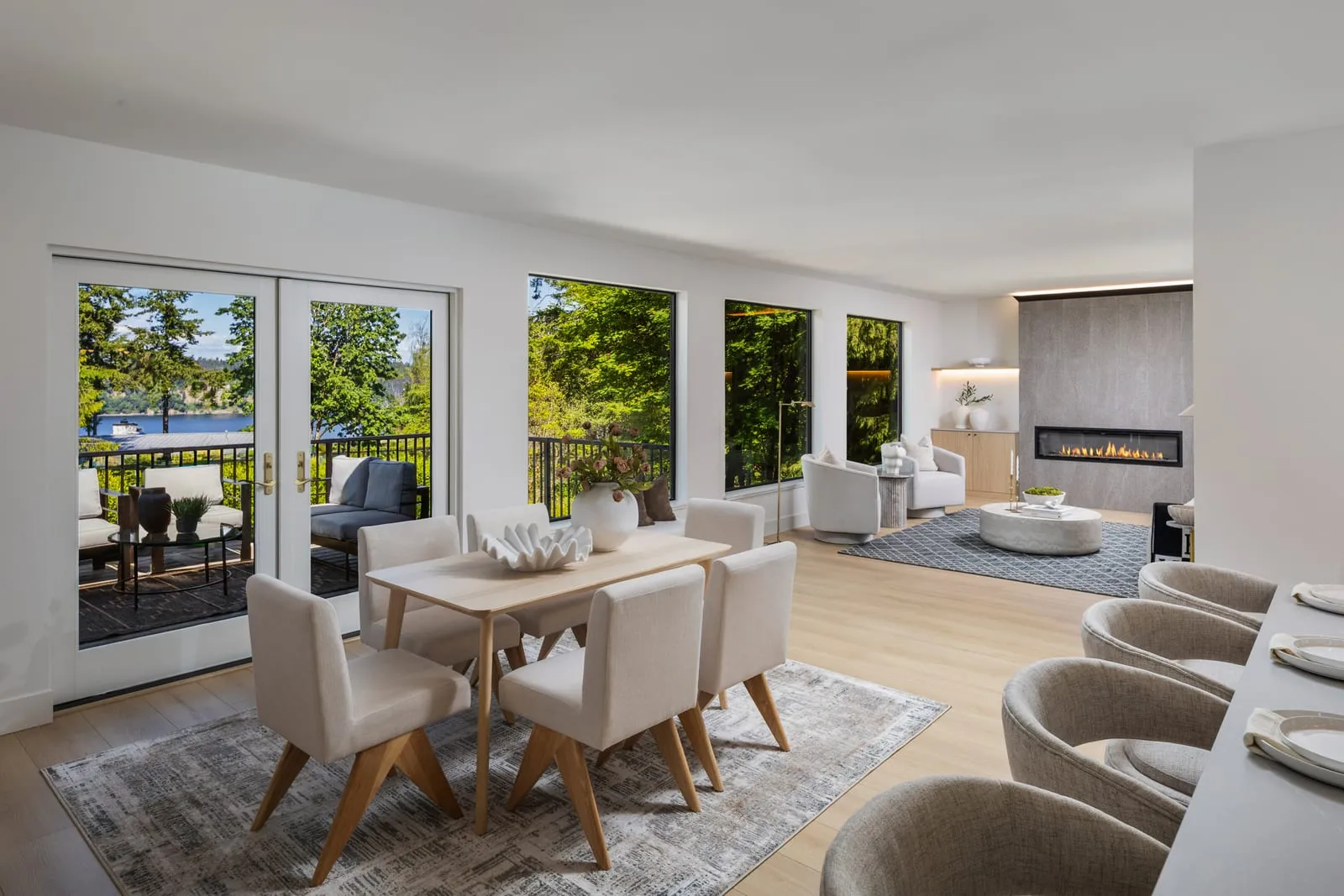 Great room opening onto a wall of windows and evergreens, the mixed daylight and interior light flambient exists to balance