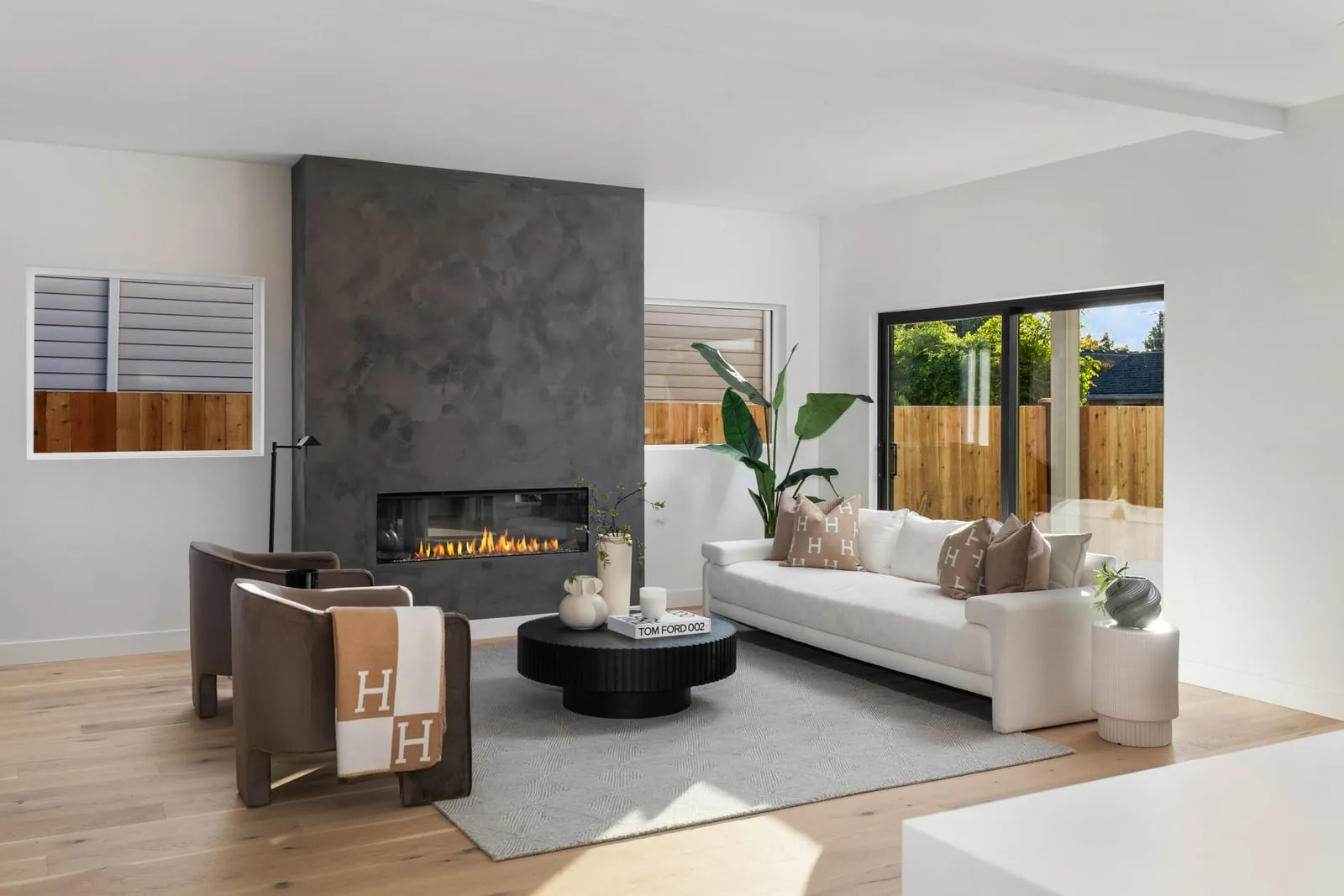 Living room with a concrete surround fireplace and a wall of glass