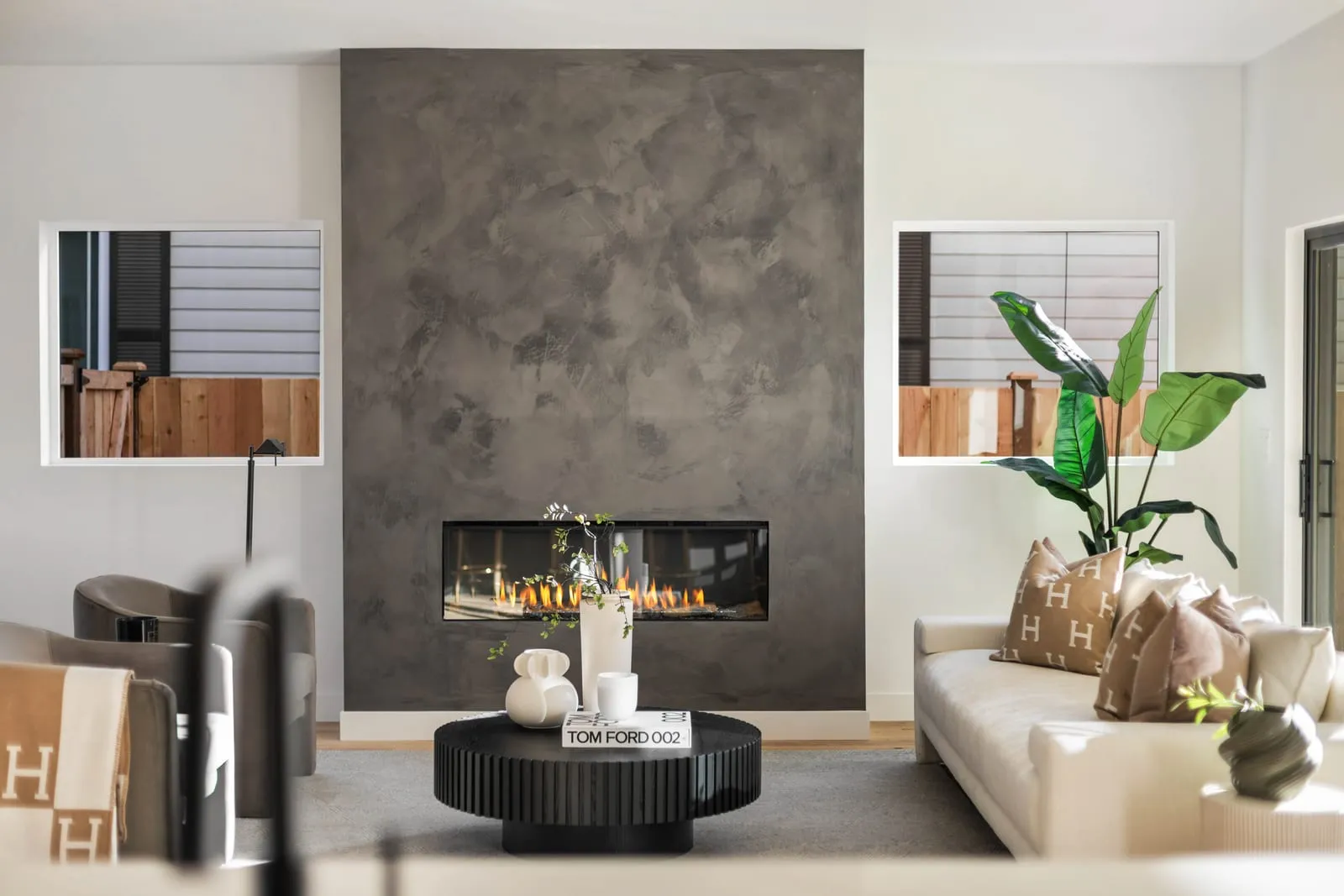 Living room with a linear fireplace and a large planter beside the glass