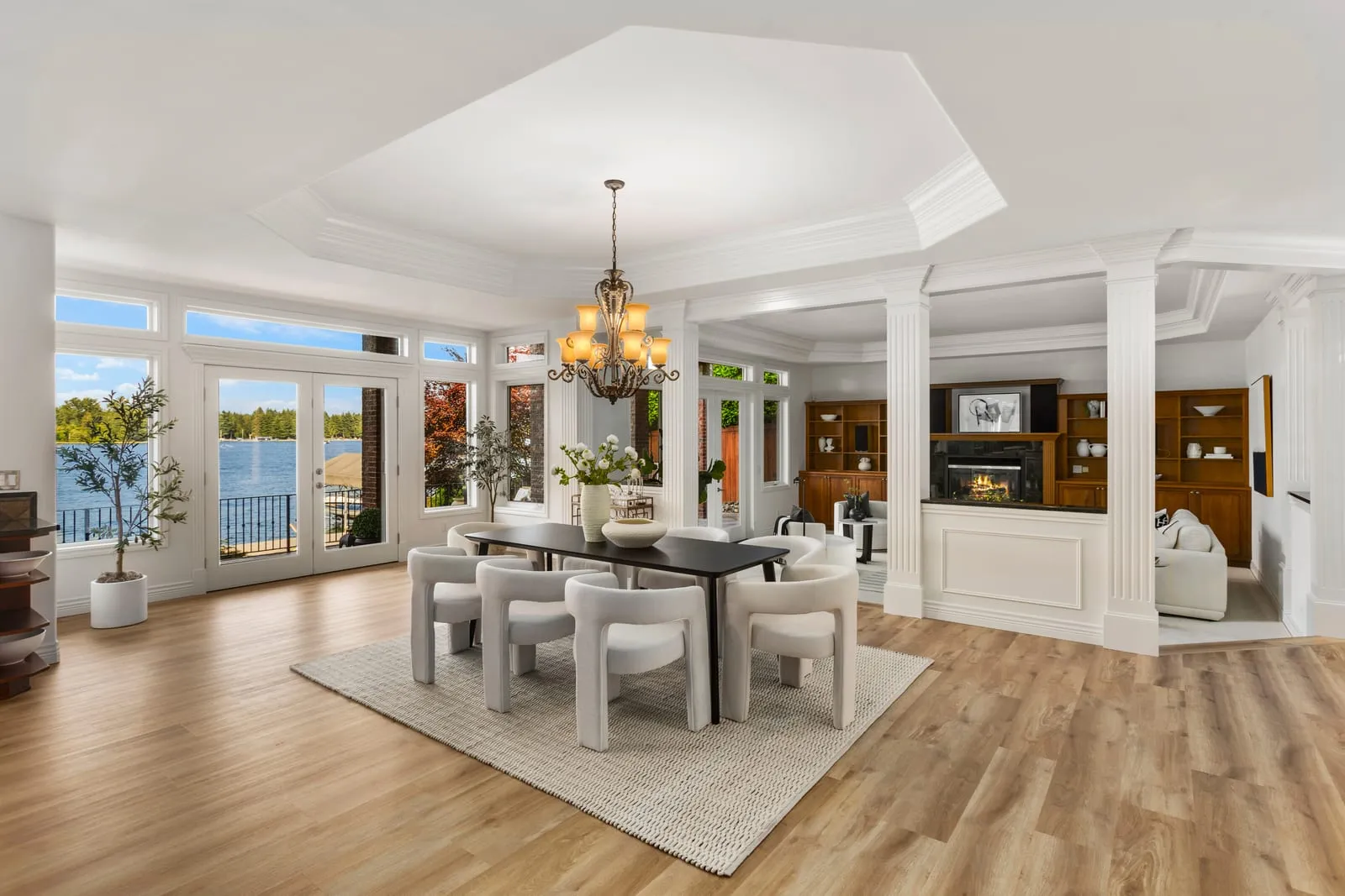 Dining room under a chandelier with a water view through full-height windows