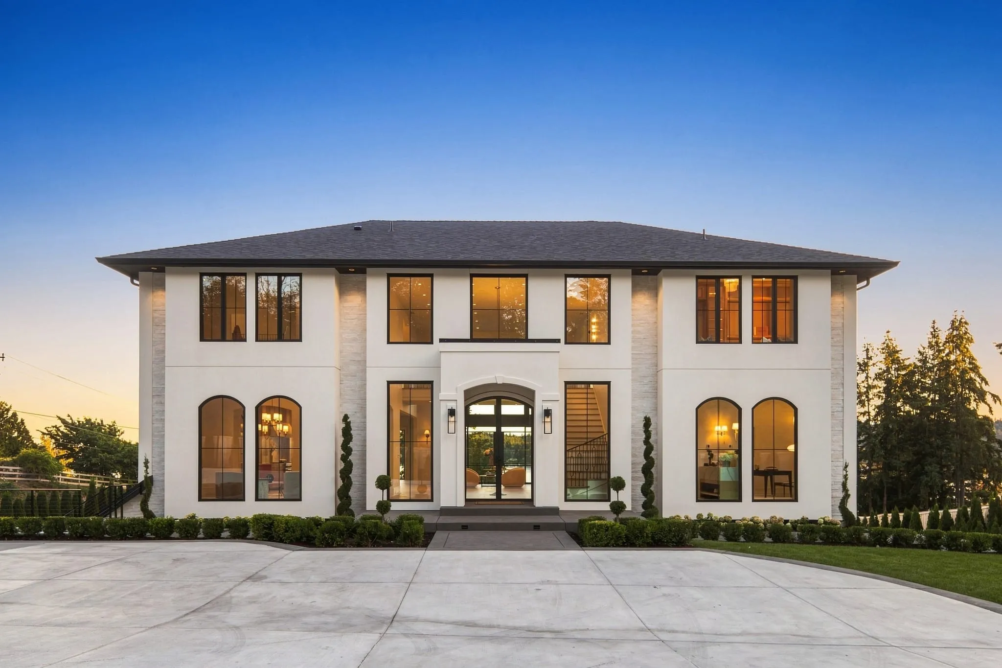 White estate at dusk, arched windows glowing warm